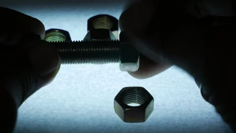 Hands Removing Metal Hex Nut from Threaded Bolt Surrounded by Nuts Stock Footage 340069287