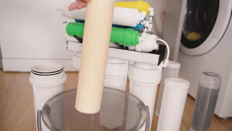 Hands Removing an Old Paper Primary Filter from the Reverse Osmosis System and Stock Footage 296572454