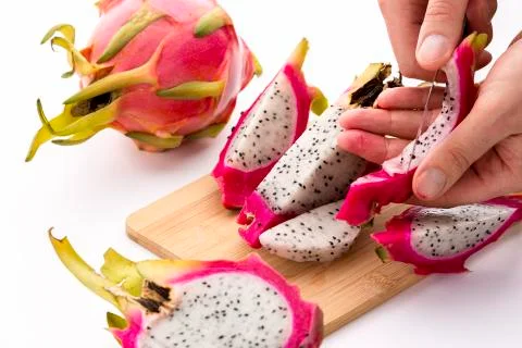 Hands removing pulp from a pitaya fruit wedge Stock Photos