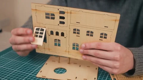 Hands removing wooden front door piece from model house kit. DIY miniature home Stock Footage 340195662