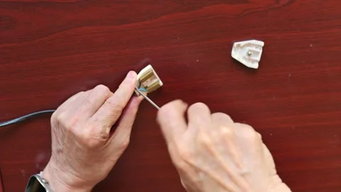 Hands Repairing an Electrical Plug with Tools on Wooden Surface Stock Footage 314898078