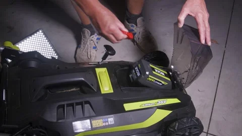 Hands Replacing Battery in Electric Lawn Mower on Concrete Stock Footage 333144069