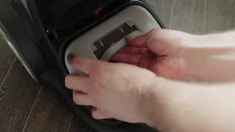 Hands replacing dust bag in vacuum cleaner interior compartment, demonstrating Stock Footage 335764310