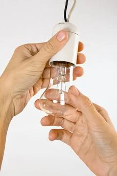 Hands replacing incandescent light bulb Stock Photos
