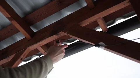 Hands Replacing LED String Light Bulbs on Wooden Terrace Structure Stock Footage 297635774