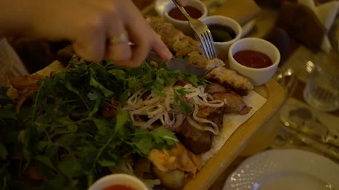 Hands with ring cut grilled minced meat kebabs amid greens, potatoes Stock-Footage 342193590