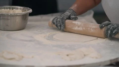 Hands roll dough in a kitchen as a chef prepares for baking. 库存影片 341498535