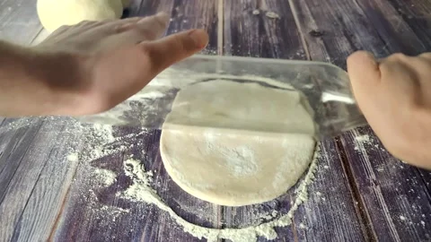 Hands roll out raw dough on a wooden table with a transparent bottle. Stock Footage 232219587