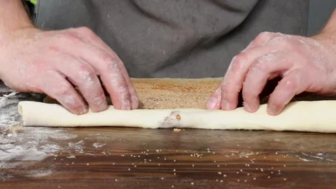 Hands roll up sweet cinnamon sugar dough into log shape to prepare homemade Stock Footage 310337430