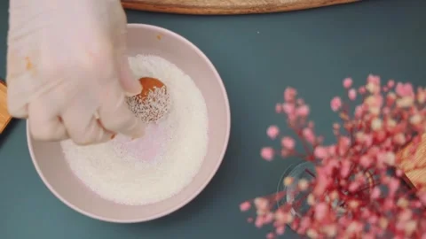 Hands rolling candy balls in coconut flakes on kitchen table Stock Footage 342877711