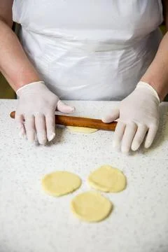 Hands rolling dough on a kitchen counter during food preparation Stock Photos