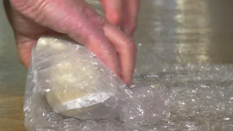 Hands rolling a fragile item in bubble wrap packaging. Stock-Footage 221252090