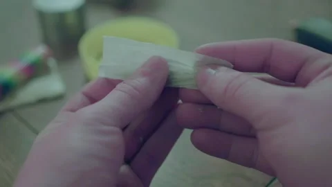 Hands rolling a joint near colored pot pipe. Video stock 169733856