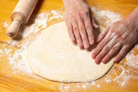 Hands with rolling-pin make dough for pizza. Italian pizza cooking preparation Stock Photos