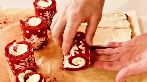Hands rolling red velvet cake with white snowflake pattern and cream filling Stock Footage 327259735