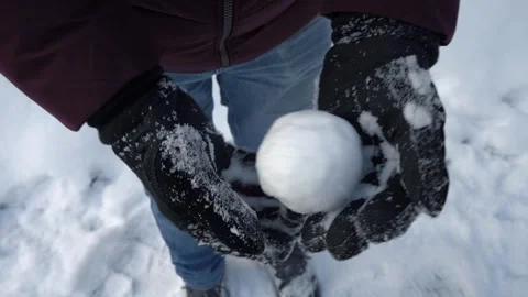 Hands rolling snowball in winter gloves outdoors, close-up winter activity Stock Footage 326824022