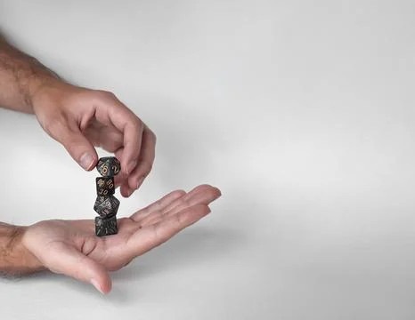 Hands rolling unique polyhedral dice in mid-air against a minimalistic Foto stock