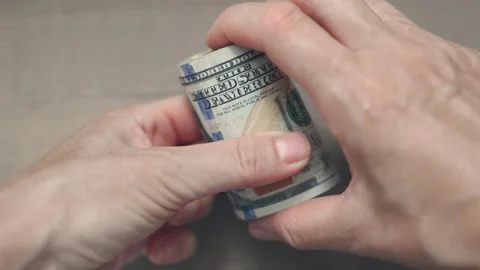 Hands rolling up US dollars stack of bills in a tube Stock Footage 160705725