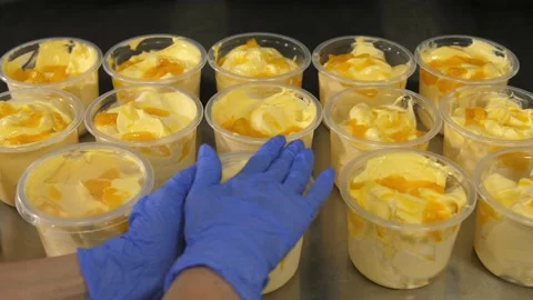 Hands in rubber blue gloves put lids on plastic buckets filled with ice cream. Video stock 192109776
