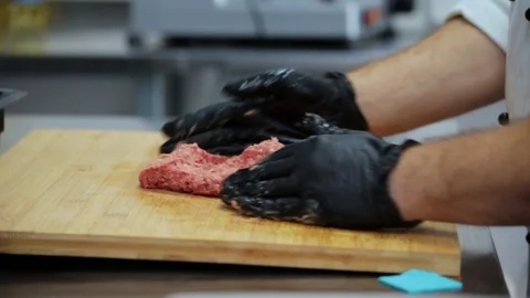 Hands in rubber gloves crumple minced meat on a wooden board Stock Footage 127201212