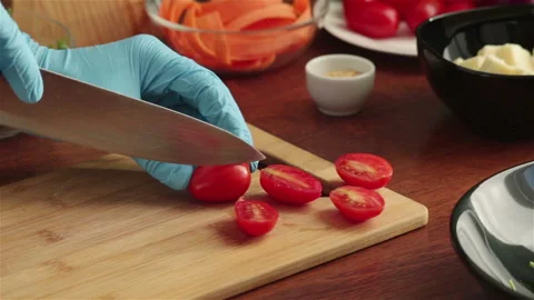 Hands in rubber gloves cut cherry tomatoes on halves close up Stock Footage 249372254