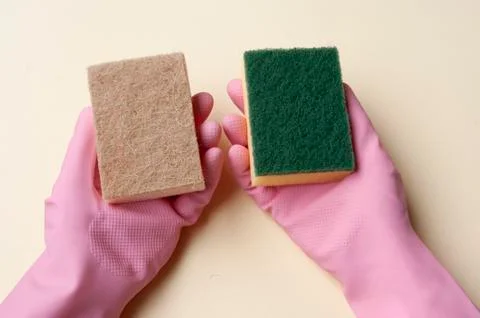 Hands in rubber gloves holding diffrent sponges. Plastic and natural sponge. Stock Photos