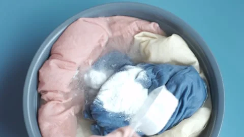 Hands in rubber gloves washing clothes in basin on blue background, top view. Stock Footage 264196451