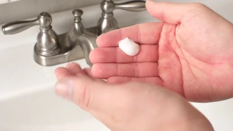 Hands Rubbing in Lotion Over Bathroom Sink Stock Footage 197008562