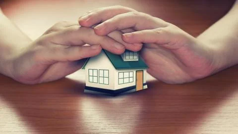 Hands saving small house Stock Photos