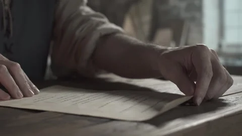 Hands of a scholar unrolling a parchment scroll with handwritten latin text Stock Footage 339232056