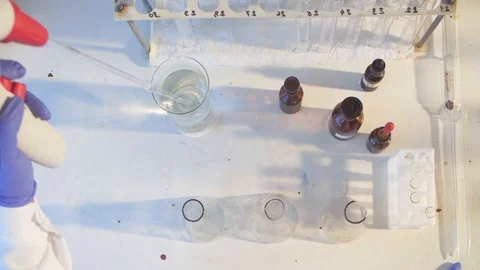 Hands of a scientist pouring solution into flasks Video stock 91609168