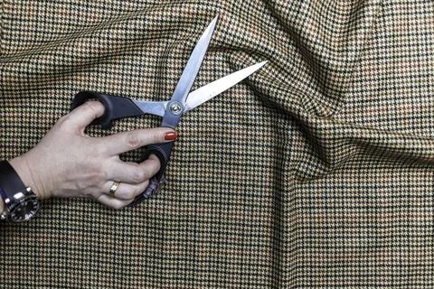 Hands with scissors on the fabric Stock Photos
