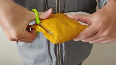 Hands with scissors opening a yellow package from an online store. Stock Footage 312897725