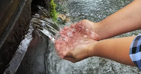 Hands scoop up clear water from a forest spring. A man drinks water from a Stock Footage 252887218