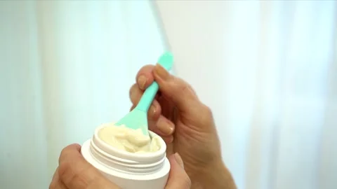 Hands scoop thick cream from jar with blue spatula. emphasis on spatula Video stock 277307811