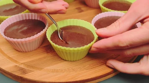 Hands scooping banana souffle from colored molds on wooden board Stock Footage 342888837