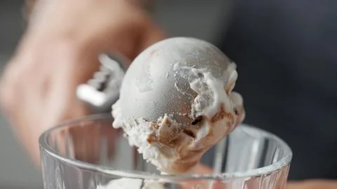 Hands Scooping A Round Portion Of Delicious Ice Cream With Topping Using An.. Stock Photos