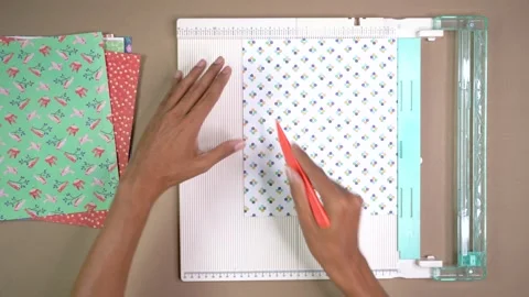 Hands Scoring Patterned Scrapbook Paper on Craft Board in DIY Arts and Crafts Stock Footage 345617071
