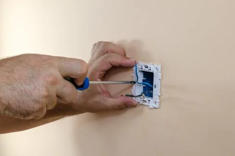 Hands, a screwdriver and a light switch Stock Photos