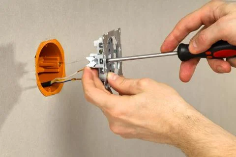 Hands with screwdriver connect the electrical outlet to the mains Stock Photos