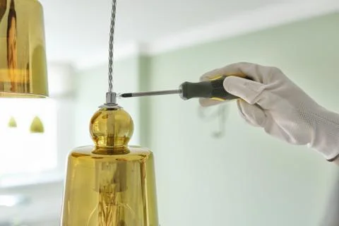 Hands with screwdriver fitting installing lamp, chandelier, closeup Stock Photos