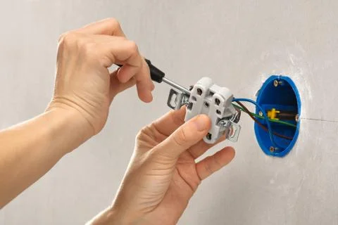 Hands with screwdriver installing electrical wall socket Stock Photos
