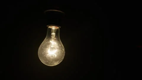 Hands Screwing Glowing Incandescent Light Bulb Into Socket in Complete Darkness Stock Footage 333828004