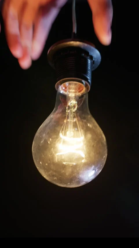 Hands Screwing Old Incandescent Lightbulb Into Socket in the Dark Stock Footage 333829465