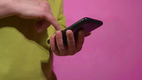 Hands scrolling on cellphone on magenta background Stock Footage 154850395