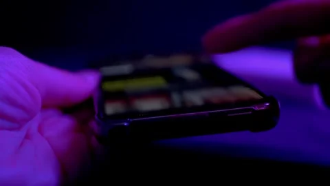 Hands Scrolling Smartphone Screen In Dark Room With Flashing Neon Color Lights 库存影片 330112324