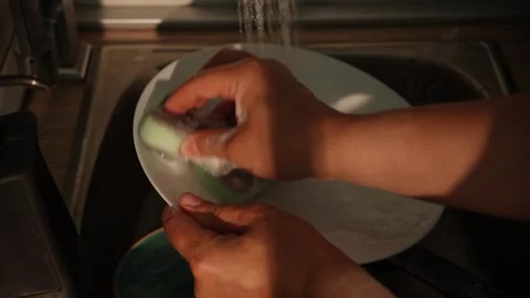 Hands scrub dirty plate with sponge under running water Stock Footage 312343831