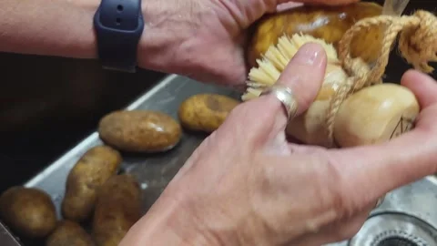 Hands Scrubbing Potatoes with Scrub Brush Under Running Water in Sink 库存影片 340112965