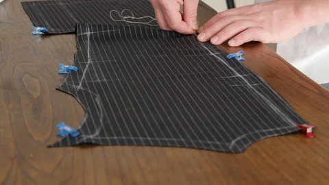 Hands of a seamstress sewing with basting thread a jacket of high Italian Stock Footage 127229333