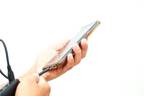 Hands securing a charger cable into a cellphone to restore power, on a plai.. Stock Photos